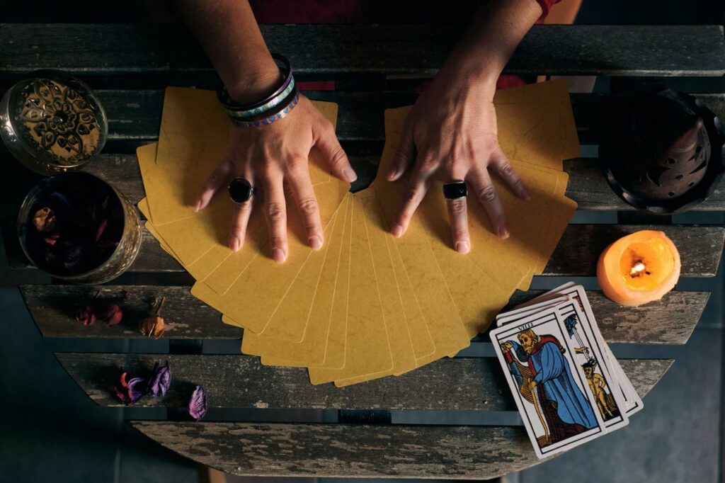 close up of a fortune teller displaying some tarot cards on a wooden table