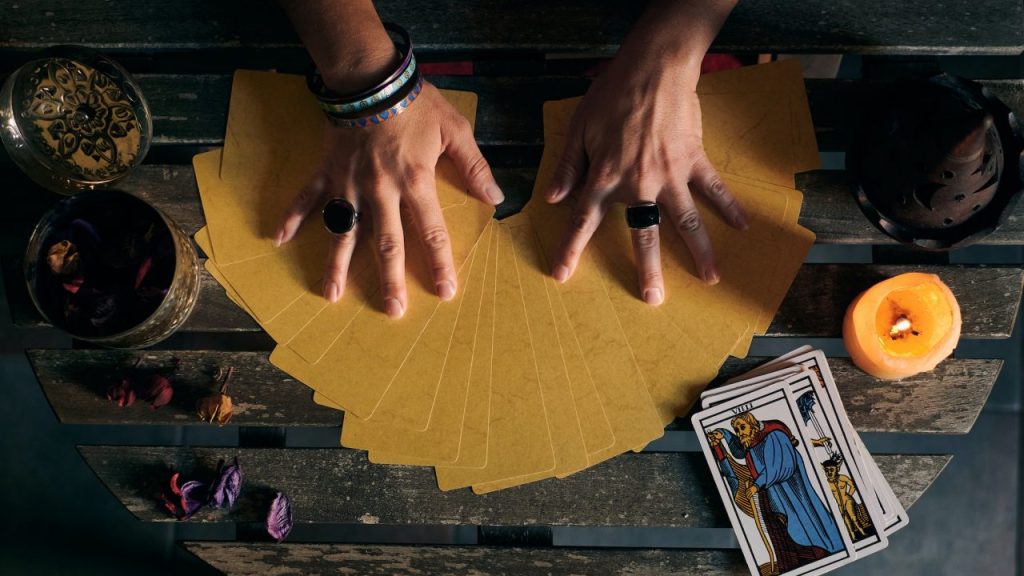 close-up-of-a-fortune-teller-displaying-some-tarot-cards-on-a-wooden-table.jpg